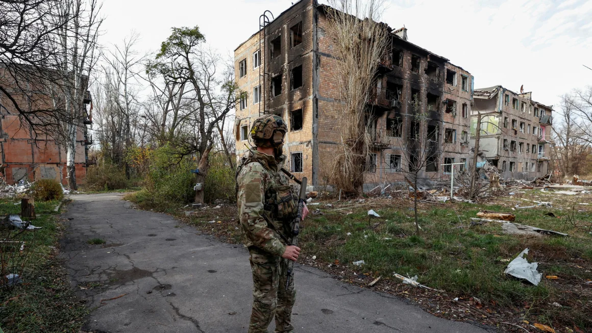 A Ukrainian serviceman stands next to heavily damaged buildings in the front line town of Avdiivka.